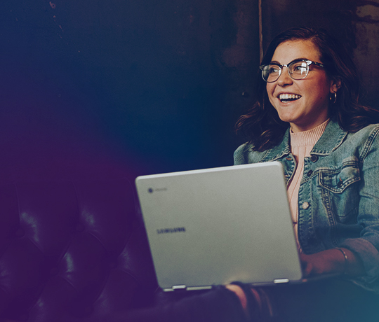 Woman with laptop sitting on couch mid-smile