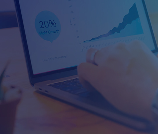 Close up of hands at laptop keyboard with chart going up shown on screen