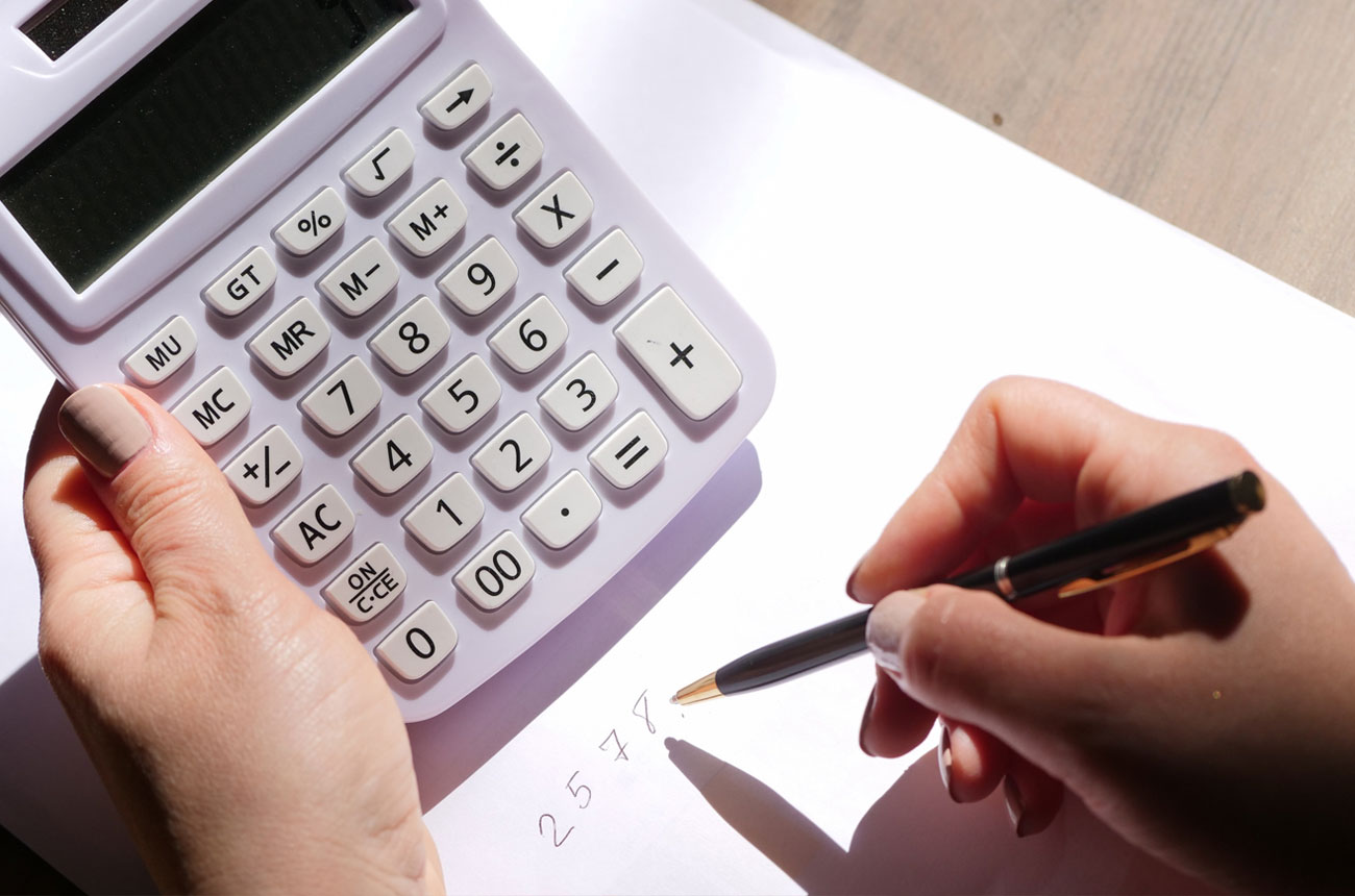 Person's hands using calculator and pen and paper