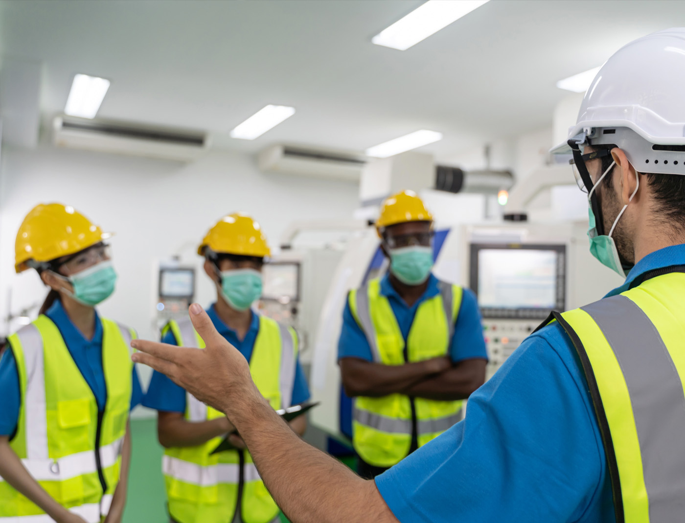 Foreman training three workers on health and safety protocol