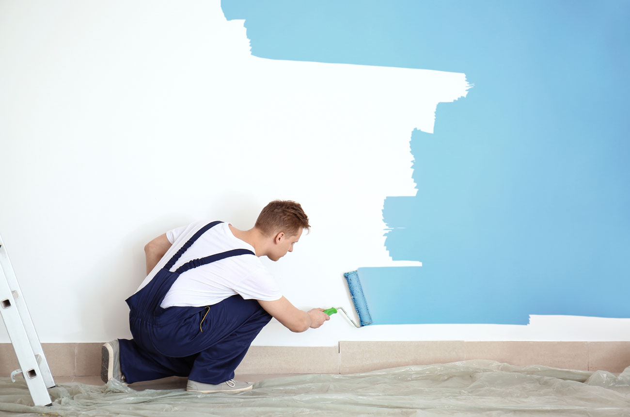 Working painting a wall blue with a roller brush