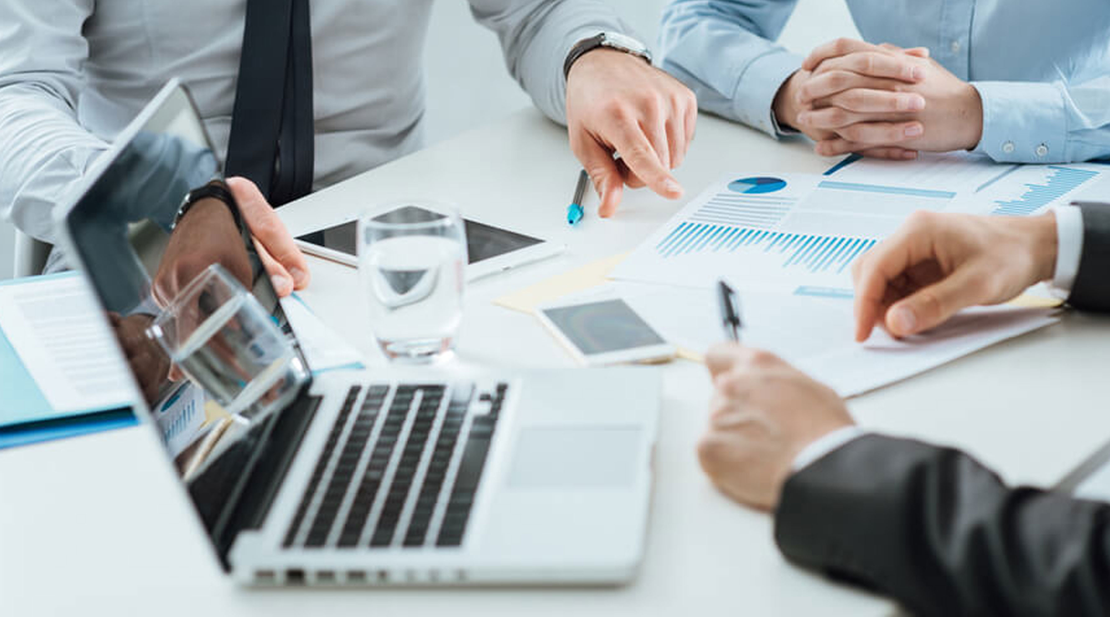Three people's hands at a desk with papers and a laptop exploring the membership lifecycle.